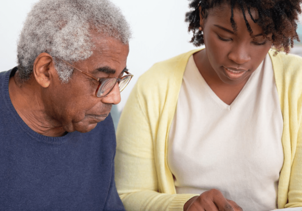 A black woman reading a book to an old man