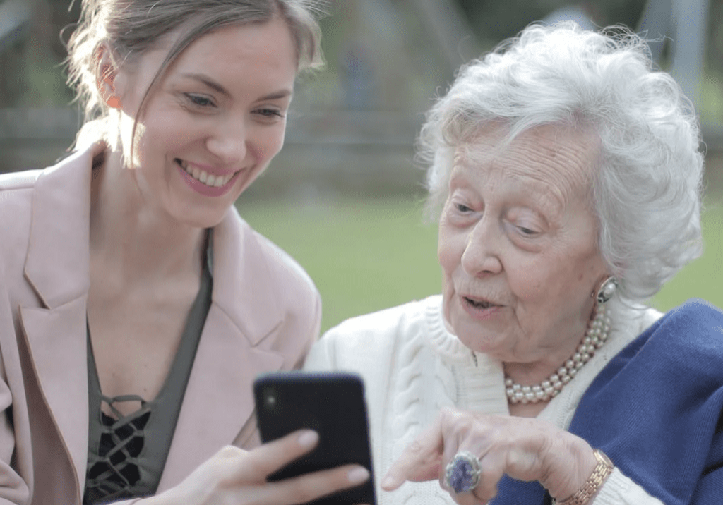 A woman showing her phone to an elderly person